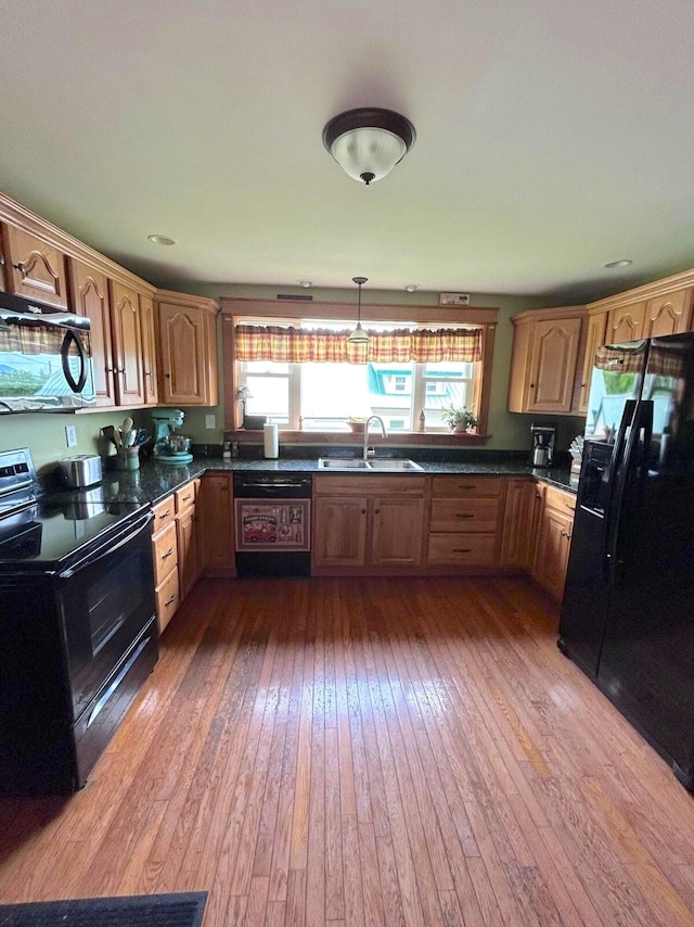 kitchen with a healthy amount of sunlight, black appliances, and hardwood / wood-style floors