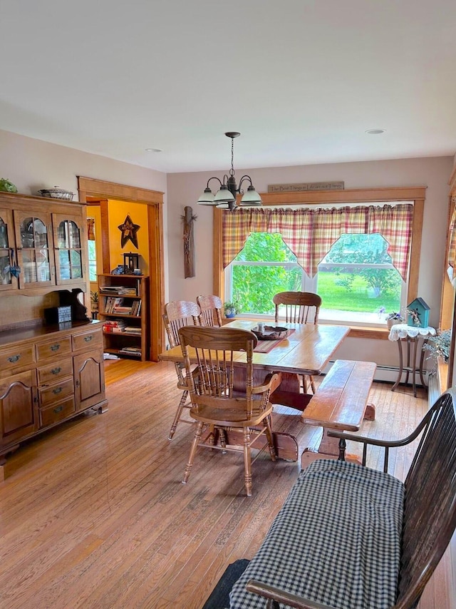 dining space featuring a baseboard radiator, light hardwood / wood-style floors, and a chandelier