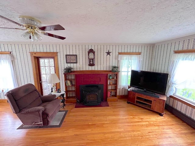 living room featuring plenty of natural light, a wood stove, light hardwood / wood-style floors, and a textured ceiling