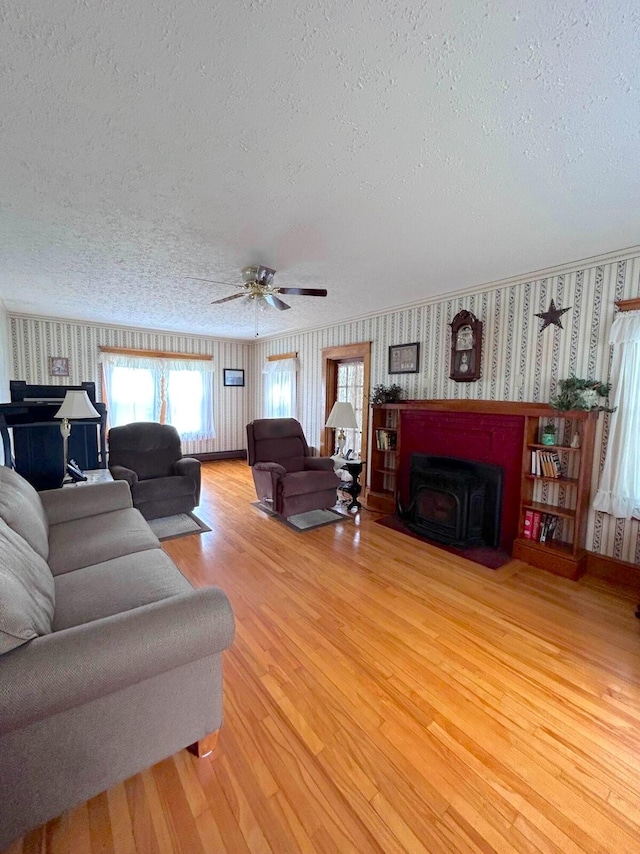 living room with ceiling fan, a textured ceiling, and light wood-type flooring