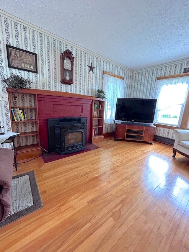 living room featuring light wood-type flooring, a wood stove, and a textured ceiling