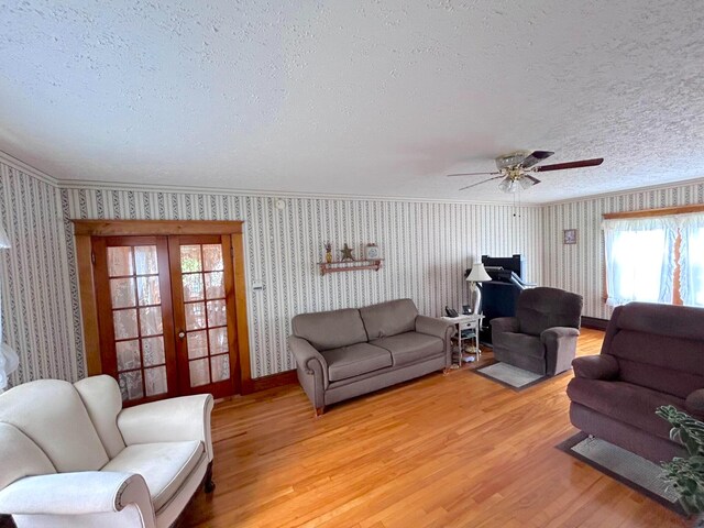 living room featuring a textured ceiling, french doors, ceiling fan, and light wood-type flooring