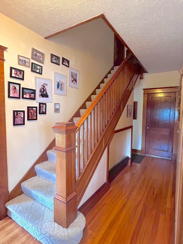 stairs featuring a textured ceiling and hardwood / wood-style floors