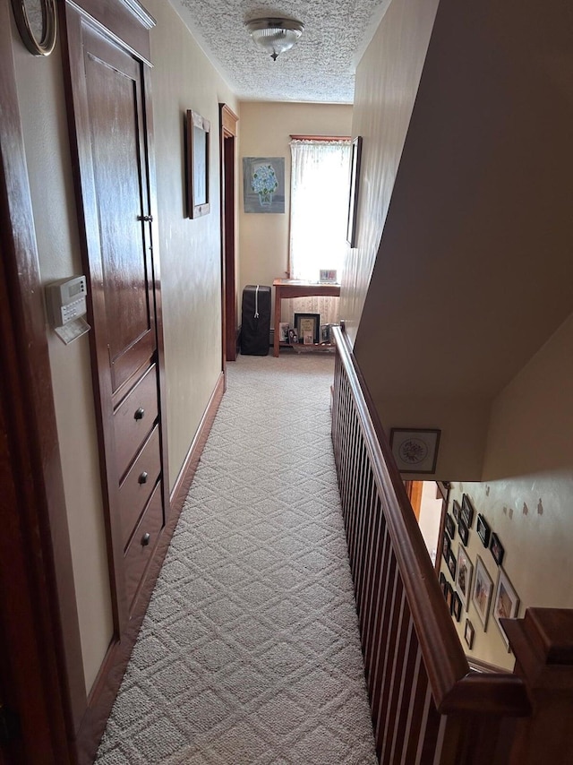 hallway with carpet and a textured ceiling