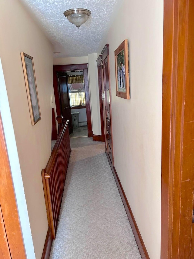 corridor featuring a textured ceiling and carpet floors