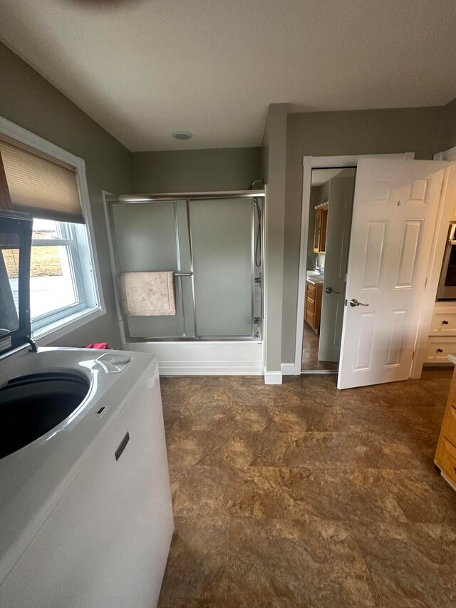 bathroom with tile flooring, an enclosed shower, and washer / clothes dryer