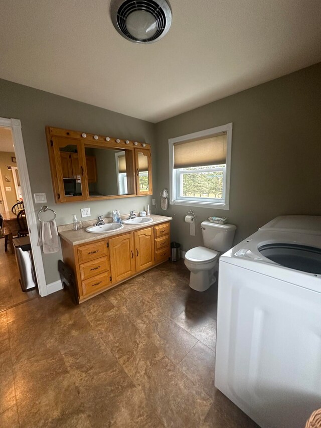 bathroom featuring toilet, washer / clothes dryer, vanity, and tile flooring