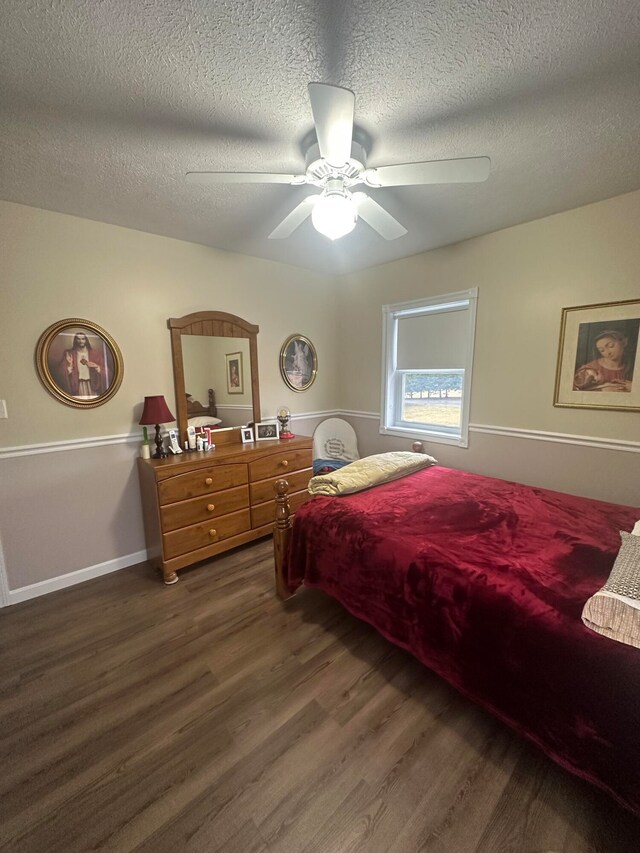 bedroom with a textured ceiling, ceiling fan, and dark wood-type flooring