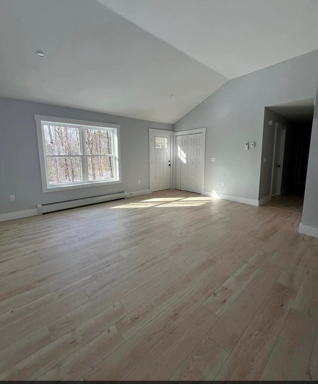 interior space with a baseboard heating unit, lofted ceiling, and hardwood / wood-style flooring