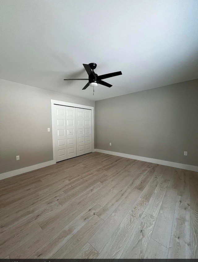 unfurnished bedroom featuring ceiling fan, a closet, and light wood-type flooring