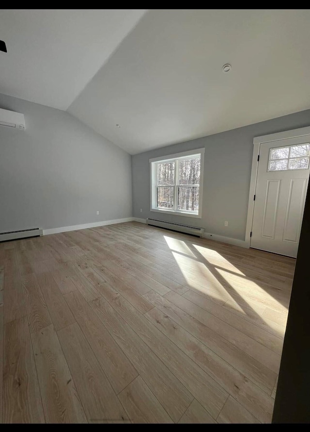 interior space featuring light wood-type flooring, a wall mounted AC, lofted ceiling, and baseboard heating