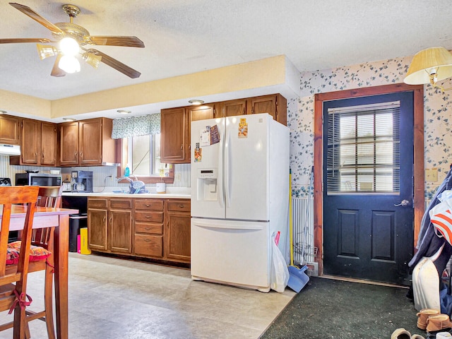 kitchen with a textured ceiling, white refrigerator with ice dispenser, ceiling fan, and light tile floors