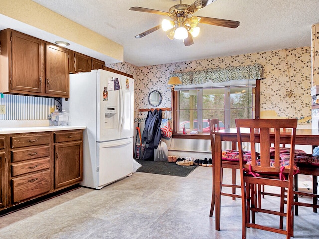 kitchen with a textured ceiling, ceiling fan, light tile floors, and white refrigerator with ice dispenser