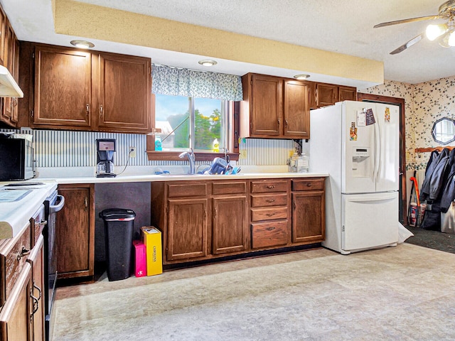 kitchen featuring a textured ceiling, white refrigerator with ice dispenser, ceiling fan, and range with electric stovetop