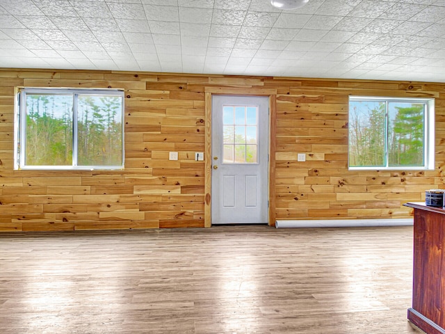 entrance foyer featuring light wood-type flooring and wooden walls