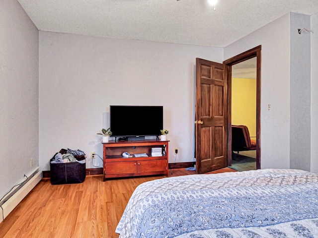 bedroom with baseboard heating, wood-type flooring, and a textured ceiling