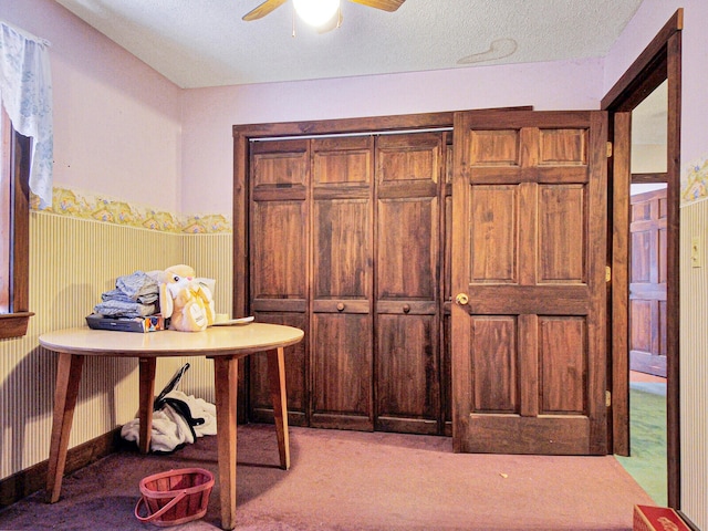 home office featuring light carpet, ceiling fan, and a textured ceiling