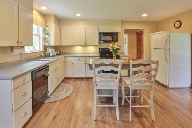 kitchen featuring sink, white cabinets, black appliances, and light wood-type flooring