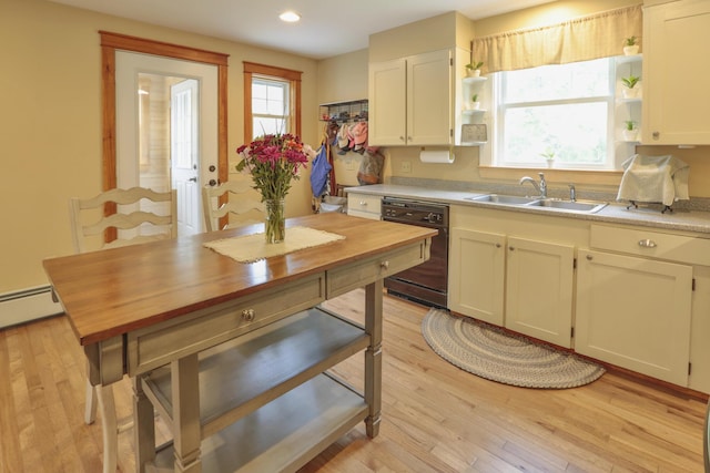 kitchen featuring light wood-type flooring, a baseboard heating unit, sink, white cabinets, and black dishwasher