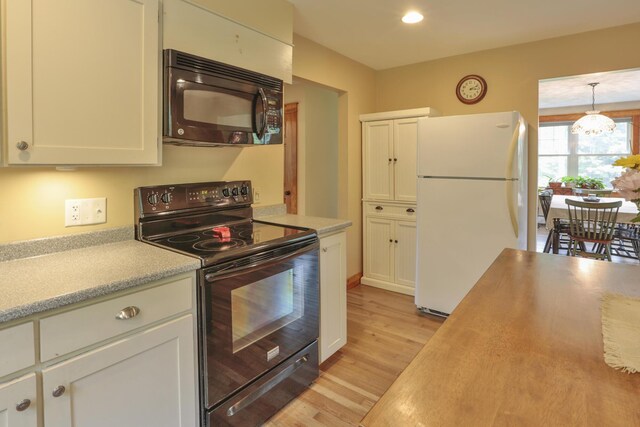 kitchen featuring pendant lighting, light hardwood / wood-style flooring, white cabinetry, and black appliances