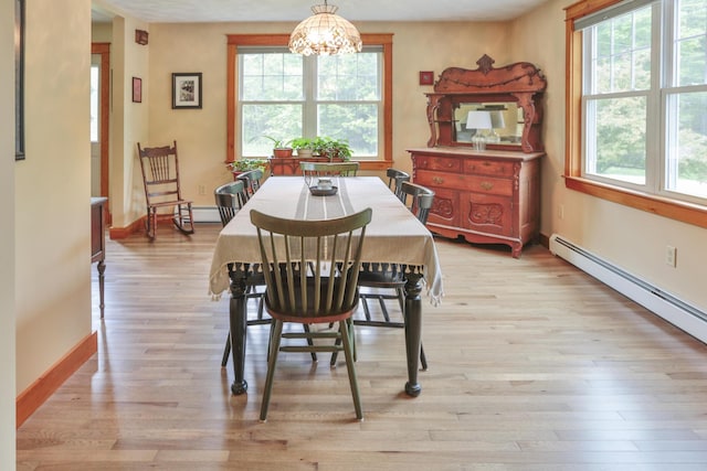 dining room featuring baseboard heating, plenty of natural light, a notable chandelier, and light wood-type flooring