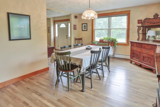 dining space featuring a chandelier, light hardwood / wood-style floors, and a baseboard heating unit