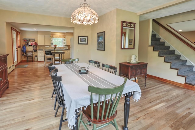 dining area featuring light hardwood / wood-style floors, baseboard heating, and an inviting chandelier