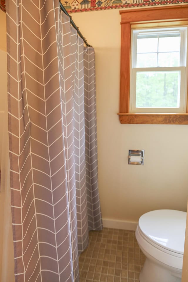 bathroom with tile patterned flooring, toilet, and walk in shower