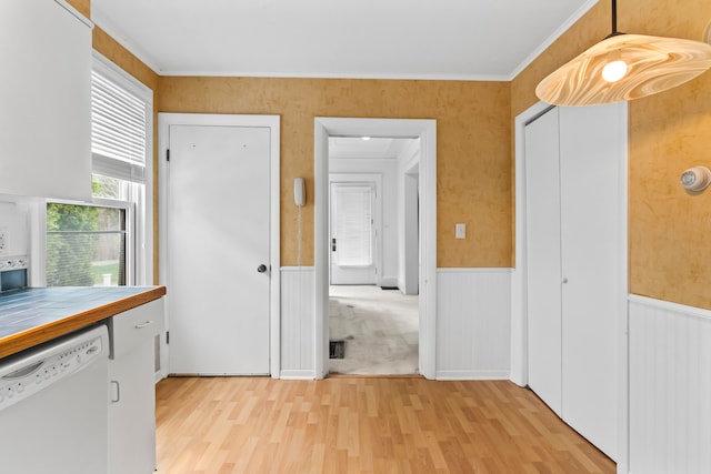 interior space with light hardwood / wood-style flooring, tile countertops, dishwasher, and ornamental molding