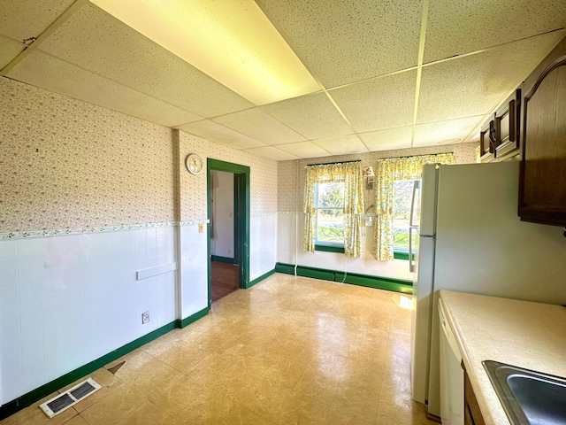 kitchen featuring baseboard heating, sink, white fridge, and a paneled ceiling