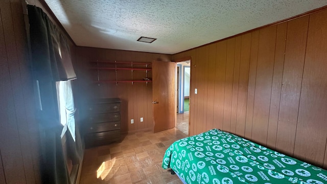 bedroom with a textured ceiling and wooden walls