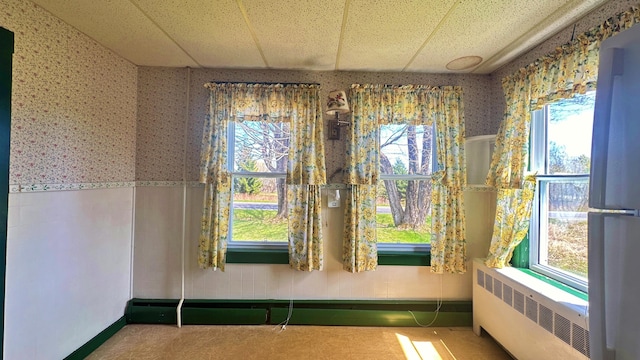 unfurnished room with a drop ceiling and radiator