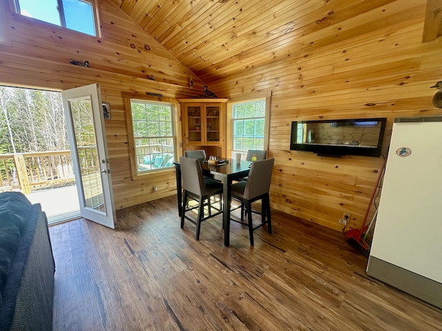 dining area featuring hardwood / wood-style floors, wooden ceiling, wood walls, and high vaulted ceiling