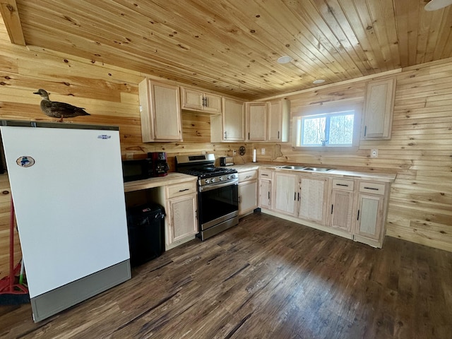 kitchen featuring stainless steel gas range, wood walls, dark hardwood / wood-style floors, and fridge