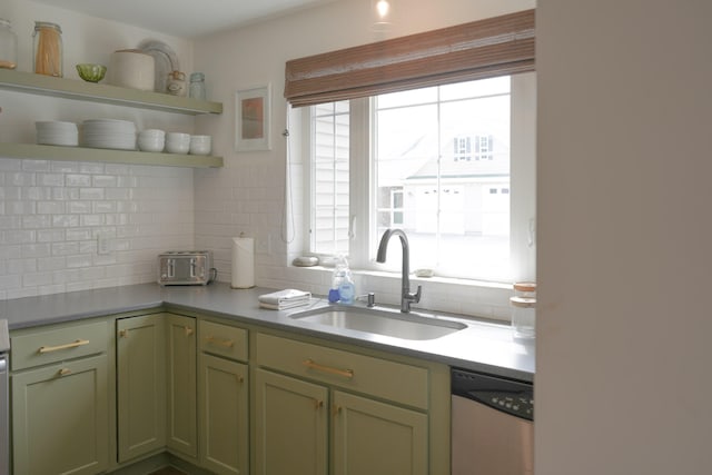 kitchen featuring stainless steel dishwasher, sink, tasteful backsplash, and green cabinetry