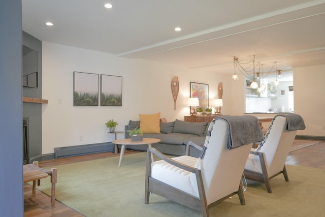 living room with hardwood / wood-style floors, a baseboard radiator, and an inviting chandelier