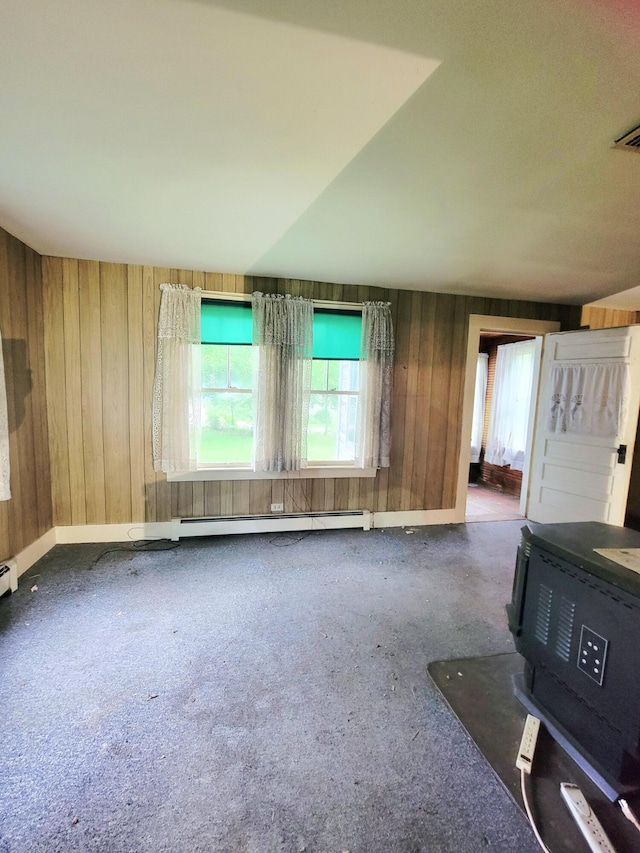 17 Otter Creek Dr, Mount Desert, ME 04660 - unfurnished living room featuring a wood stove, wood walls, a baseboard radiator, and carpet flooring