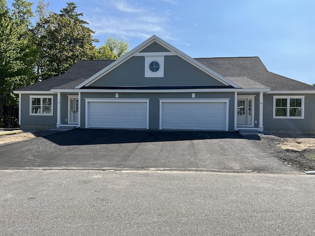 view of front facade with a garage, a shingled roof, and aphalt driveway