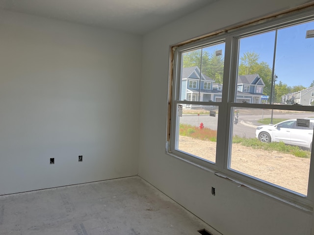 spare room featuring a residential view and unfinished concrete floors