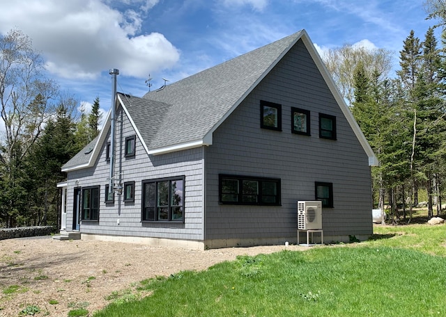 rear view of property featuring entry steps, ac unit, a lawn, and roof with shingles