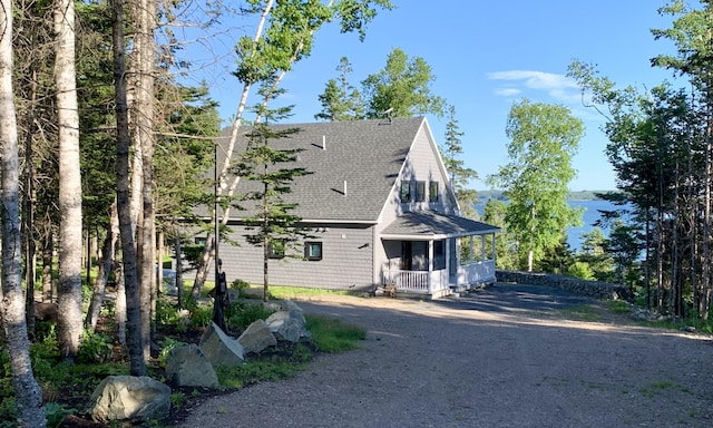 view of side of home featuring driveway, a porch, and a shingled roof