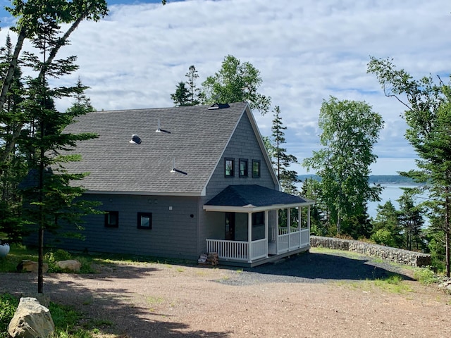 view of front of house featuring covered porch, roof with shingles, and dirt driveway