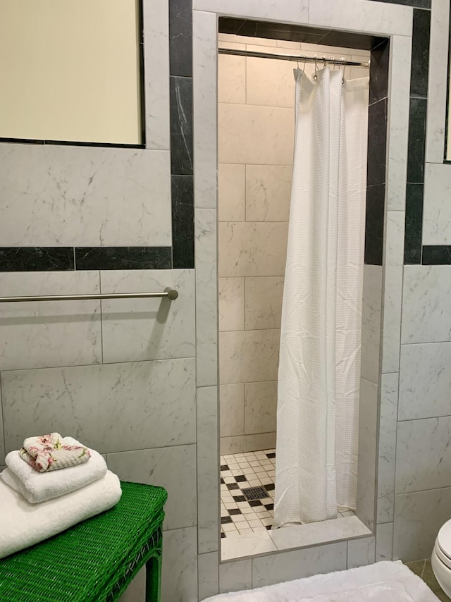 bathroom with toilet, a stall shower, and tile walls