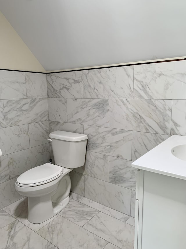 half bathroom with marble finish floor, vanity, and toilet