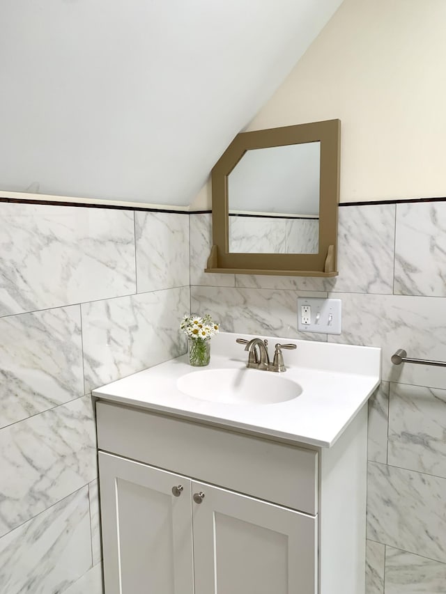 bathroom featuring tile walls, vaulted ceiling, and vanity