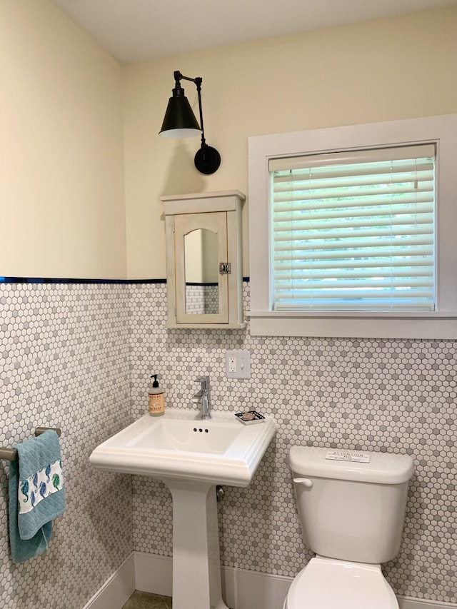 half bathroom featuring toilet, tile walls, and wainscoting