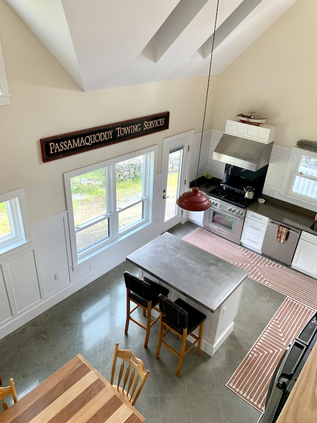 dining area with plenty of natural light, lofted ceiling, a wainscoted wall, and a decorative wall