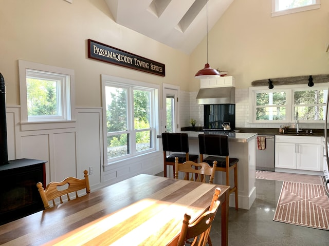 dining space featuring high vaulted ceiling, a decorative wall, and wainscoting