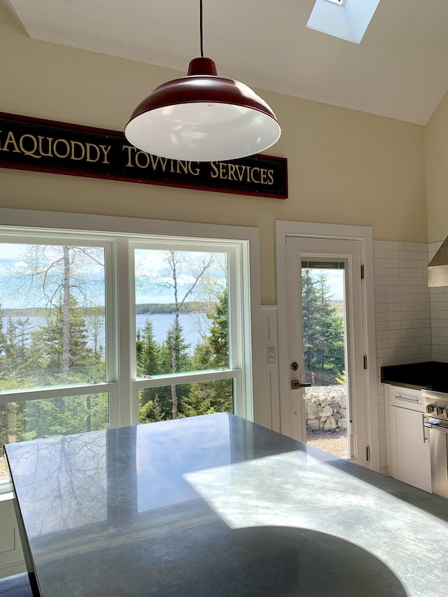 unfurnished dining area with a water view, vaulted ceiling with skylight, and a wealth of natural light