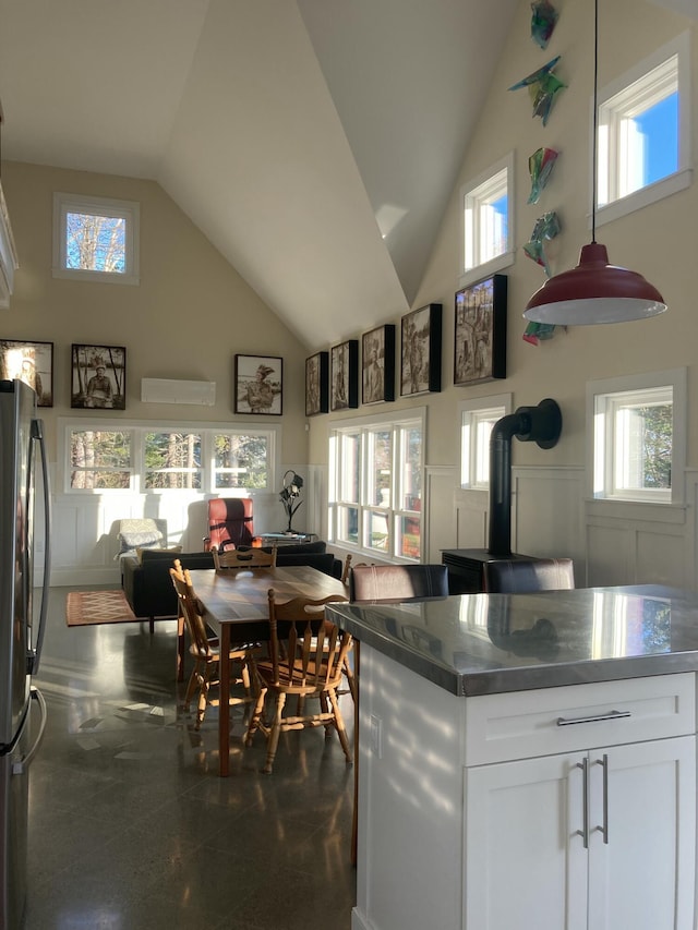 kitchen with a wainscoted wall, high vaulted ceiling, a decorative wall, and freestanding refrigerator